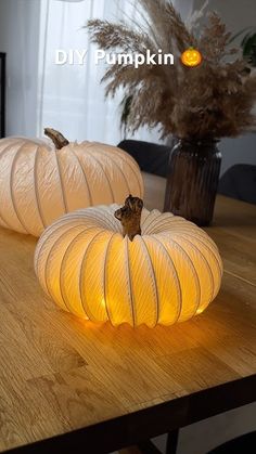 two white pumpkins sitting on top of a wooden table