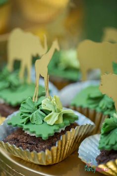 some cupcakes with green frosting and giraffe decorations on top of them