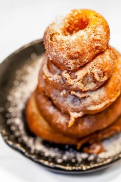 a stack of doughnuts sitting on top of a black and white plate with powdered sugar