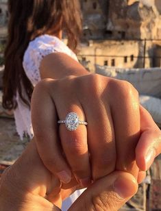 a woman is holding up her engagement ring