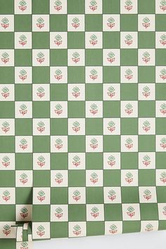 a green and white checkered wallpaper with red flowers on the top, next to a pair of scissors