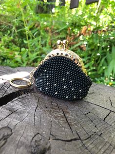 a black beaded purse sitting on top of a wooden stump