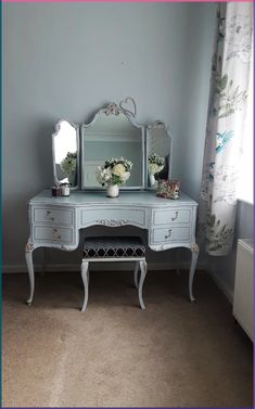 a bedroom with a dresser, mirror and vase on the floor in front of a window