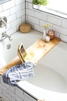 a person laying in a bathtub with their feet on a wooden shelf next to the tub