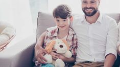 a man sitting next to a little boy holding a stuffed animal