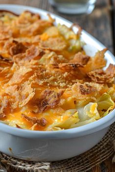 a casserole dish with cheese and other toppings in a white bowl on a wooden table