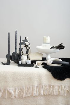 a table topped with black and white items on top of a blanket next to candles