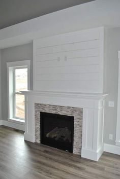 an empty living room with a fireplace in the center and white paint on the walls