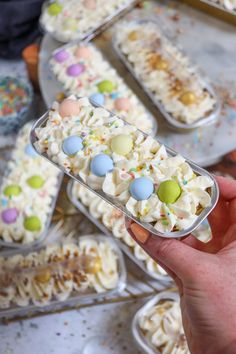 a person holding up a plastic container filled with cake and marshmallow candies