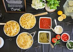 the table is full of different types of pasta and condiments, including tomatoes