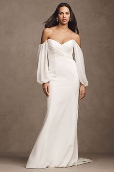 a woman in a white wedding dress with long sleeves and an off the shoulder top