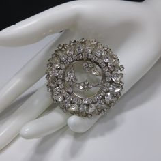 *Description: This is a gorgeous clear rhinestone wedding brooch from the 1960s. The two tiered design has clear rhinestones in teardrop cuts and chaton cuts throughout. The center of the brooch is open and there are three sets of rhinestones which look like flowers on a silver tone stem. This brooch would be a great to wear to a wedding or give the bride as an heirloom gift. It would be beautiful to wear to any special occasion. This brooch would be a great addition to your vintage jewelry coll Glamorous Silver Brooch For Wedding, Vintage Sparkling Wedding Brooches, Glamorous Rhinestone Wedding Brooches, Wedding Costume Jewelry Brooches With Sparkling Stones, Wedding Crystal Brooches With Sparkling Stones, Wedding Silver Brooches With Sparkling Stones, Brooch Wedding, Formal Earrings, Vintage Christmas Gifts