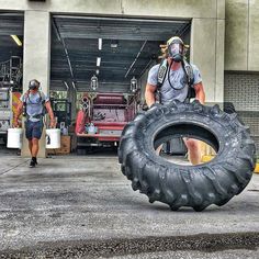 two men in front of a garage with large tires