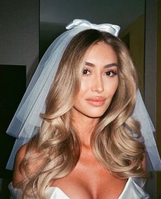 a woman with blonde hair wearing a white veil and wedding dress is looking at the camera