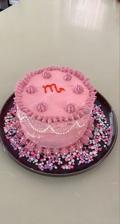 a pink cake sitting on top of a black plate