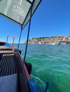 the back end of a boat in clear blue water with houses and buildings in the background