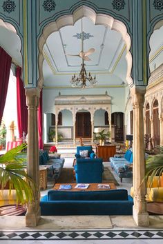 a living room filled with blue couches and lots of furniture under a chandelier