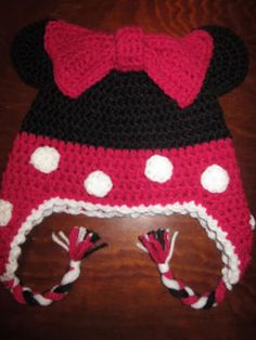 a crocheted minnie mouse hat on top of a wooden table with candy canes