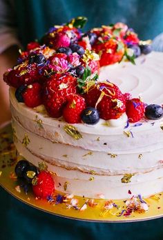 a white cake topped with berries and sprinkles on top of a yellow plate