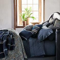 a bed sitting next to a window in a bedroom under a blanket on top of a chair