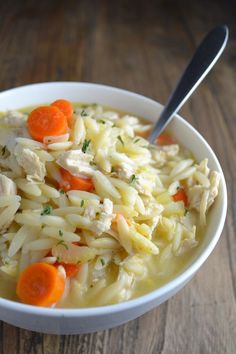 a bowl of chicken noodle soup with carrots and parsley