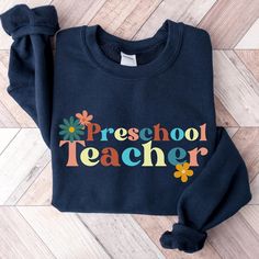 Welcome back the new school year with this very cute retro navy blue preschool teacher sweatshirt.  Embrace sweater weather and show up to class with this cozy and comfortable fall teacher sweater. This sweater is made from polyester and cotton. This combination helps designs come out looking fresh and beautiful.  The collar is ribbed knit, so it retains its shape even after washing.   Knit in one piece using tubular knit, it reduces fabric waste and makes the garment more attractive.  There are no itchy side seams on these sweaters.  .: 50% Cotton 50% Polyester .: Medium-heavy fabric 8.0 oz. .: Loose fit .: Sewn in label .: Runs true to size Care Instructions:  Machine wash: warm (max 40C or 105F); Non-chlorine: bleach as needed; Tumble dry: medium heat; Do not iron; Do not dryclean. Orde Retro Blue Tops For School, Blue Pre-shrunk School Spirit Sweatshirt, Blue Crew Neck Tops For Back To School, Blue Tops For College Back To School, Blue School Spirit Sweatshirt For School, Blue School Spirit Sweatshirt, Blue Pre-shrunk Sweatshirt For Fall, Blue Cotton Back To School Tops, Blue Cotton Top For Back To School