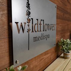 a metal sign that reads wildflower medispa on the side of a wooden wall