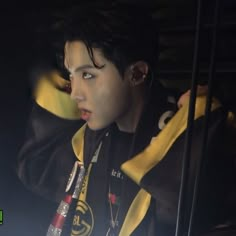 a young man with ear buds on his ears wearing a black and yellow hoodie