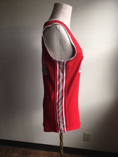 "Vintage spots sleeveless jersey label- Athletic Supply label size 38 (please go by measurements) red with grey and white side stripes and neck stripes 21 patches on front and back good condition w/wear normal to age no fabric info tag feels partly elastic/stretchy measures, lying flat, shoulder- 13 1/4\" chest- 18\" hem- 18 1/4\" length- 29\"" Team Spirit Red Sleeveless Tops, Red Sleeveless College Tops, Red Sleeveless Tops For College, Collegiate Red Sleeveless Top, Red Collegiate Sleeveless Top, Red Three Stripes Top For College, Red Three-stripes Tops For College, Sleeveless Team-colored Tops For College, Red Cotton Sporty Tank Top