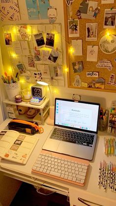 an open laptop computer sitting on top of a white desk next to a wall covered in pictures