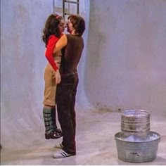 a man and woman kissing in front of a bucket