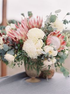 a vase filled with white and pink flowers on top of a blue cloth covered table