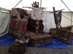 an old pirate ship made out of wood and other items on display in a tent