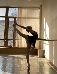 a ballerina is practicing her moves in an empty room with sunlight streaming through the windows