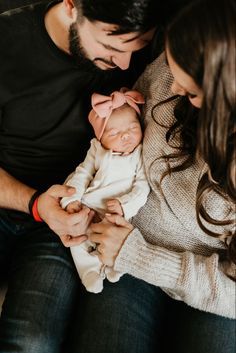 a man and woman holding a baby in their arms