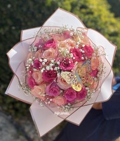 a person holding a bouquet of flowers with butterflies on the top and pink roses in the middle