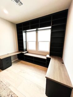 an empty room with black bookshelves, desks and drawers on the wall