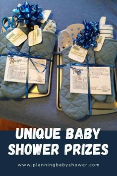 two baby shower prizes sitting on top of a bed with blue bows and tags attached to them