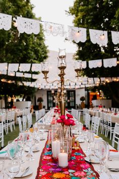 a long table is set up with white chairs and red runneres for an outdoor dinner