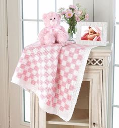 a pink teddy bear sitting on top of a table next to a vase with flowers