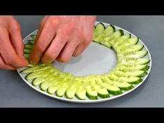 a person cutting cucumber slices on a plate