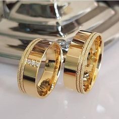 two gold wedding rings sitting on top of a white counter