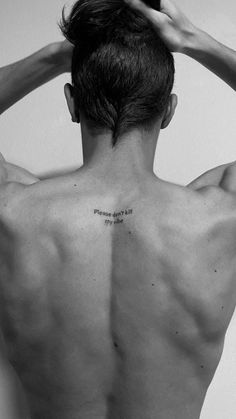 the back of a man's head with his hands behind his head and an inscription on his chest