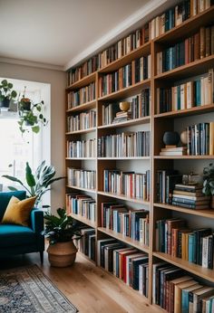 a bookshelf filled with lots of books next to a couch and potted plant