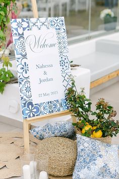 a blue and white wedding sign sitting on top of a table next to some flowers