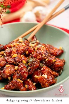 a bowl filled with meat and chopsticks on top of a table