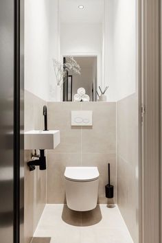 a white toilet sitting next to a sink in a bathroom under a mirror above it