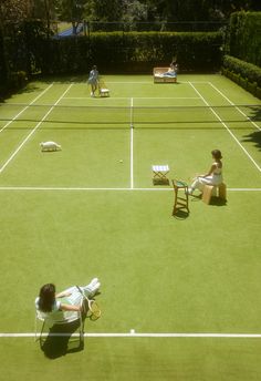 two people sitting on lawn chairs in the middle of a tennis court