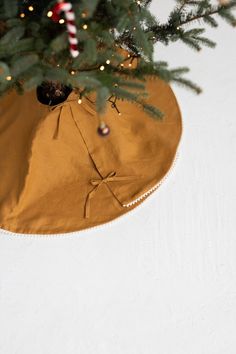 a christmas tree skirt hanging from the top of a small fir tree in front of a white wall