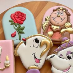 beauty and the beast cookies on a wooden table with decorations around them, all decorated to look like disney characters